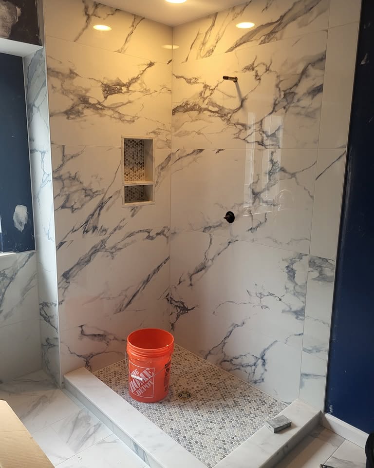 After: the same shower finished in floor-to-ceiling marble-look tile